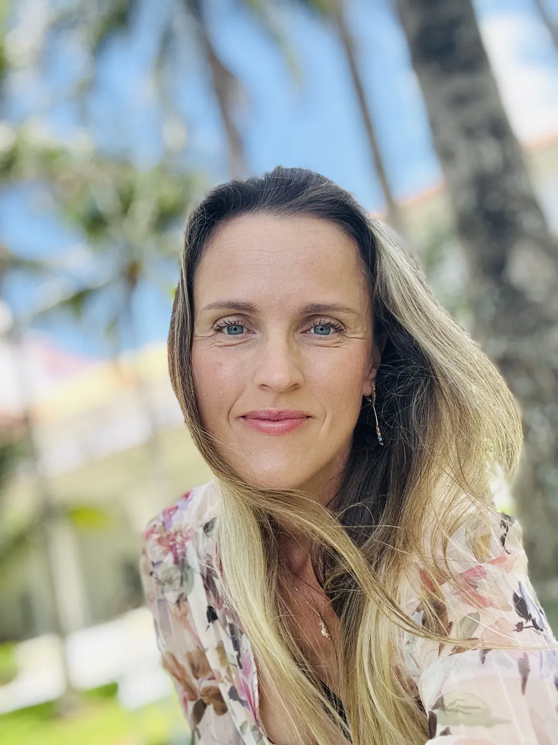 Maria smiling outdoors in a floral blouse